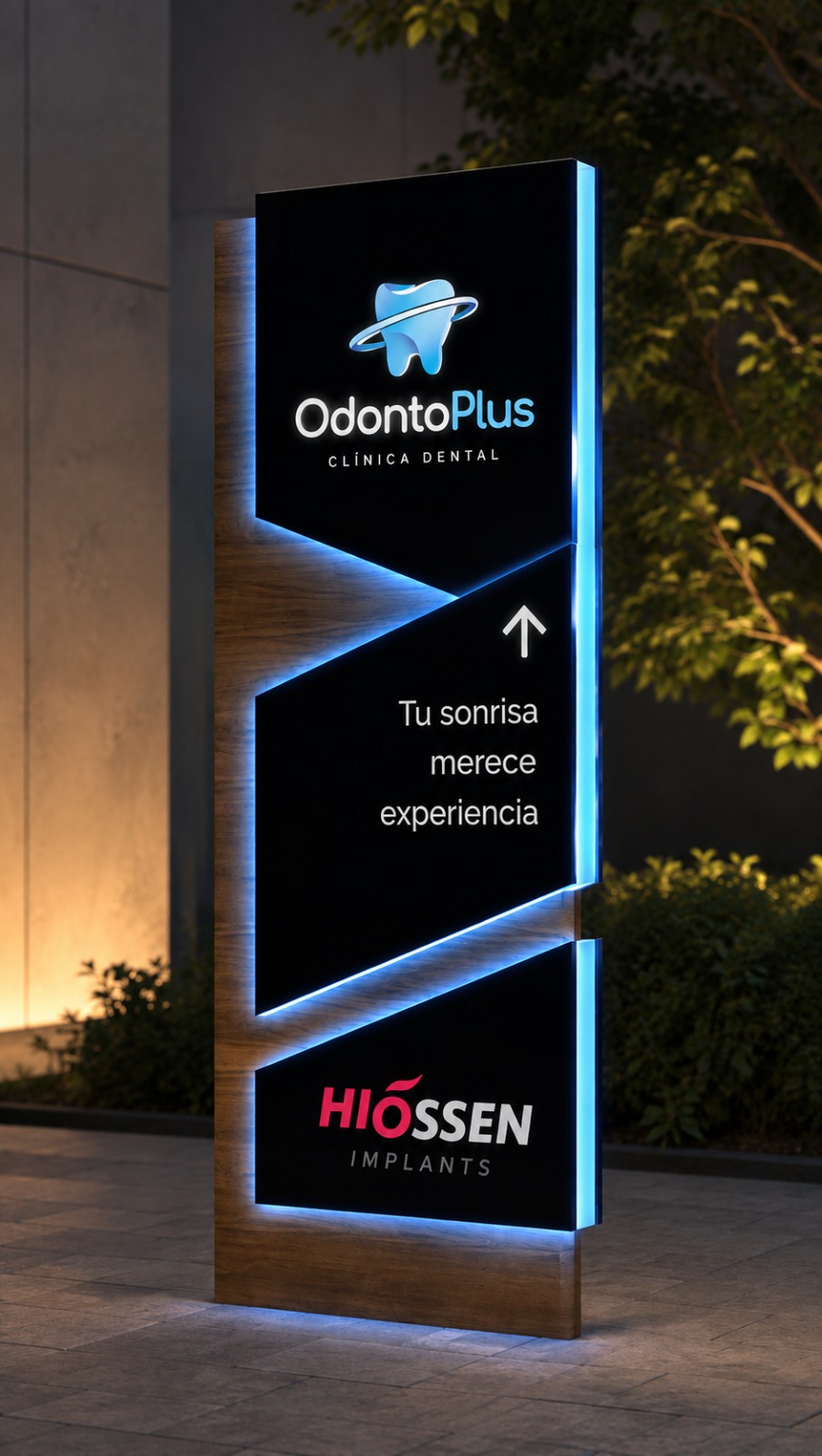 Render del tótem propuesto de noche: volumen símil madera con panel negro, logotipo OdontoPlus retroiluminado, el mensaje Tu sonrisa merece experiencia y el logotipo Hiossen Implants
